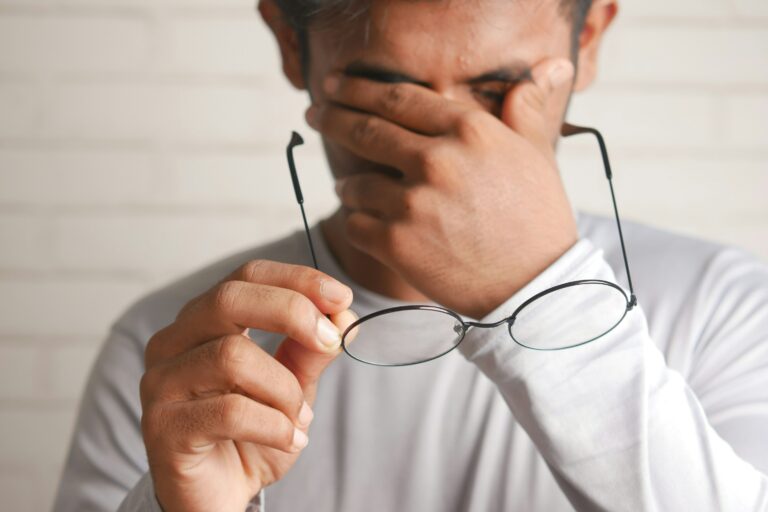 Das Bild zeigt einen Mann, der sich erschöpft die Augen reibt und eine Brille in der Hand hält, was auf gesundheitliche Beschwerden oder Müdigkeit hinweist. Die elektronische Arbeitsunfähigkeitsbescheinigung (eAU) ermöglicht es, Krankmeldungen schnell und effizient digital an den Arbeitgeber und die Krankenkasse zu übermitteln. Dies erleichtert den Prozess der Krankmeldung und reduziert den administrativen Aufwand.