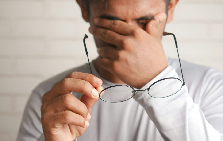 Das Bild zeigt einen Mann, der sich erschöpft die Augen reibt und eine Brille in der Hand hält, was auf gesundheitliche Beschwerden oder Müdigkeit hinweist. Die elektronische Arbeitsunfähigkeitsbescheinigung (eAU) ermöglicht es, Krankmeldungen schnell und effizient digital an den Arbeitgeber und die Krankenkasse zu übermitteln. Dies erleichtert den Prozess der Krankmeldung und reduziert den administrativen Aufwand.