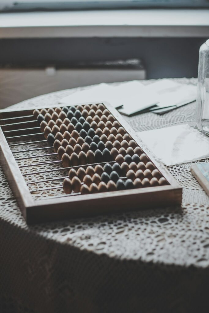 Ein Abakus, ein traditionelles Recheninstrument, liegt auf einem Tisch und symbolisiert die manuelle Berechnung von Zahlen. Tantiemen, als zusätzliche Vergütungen für kreative oder geschäftliche Leistungen, erfordern präzise Berechnungen, um die korrekte Auszahlung sicherzustellen. Der Abakus steht hier als Symbol für die Genauigkeit und Sorgfalt, die bei der Berechnung und Verwaltung von Tantiemen erforderlich ist.